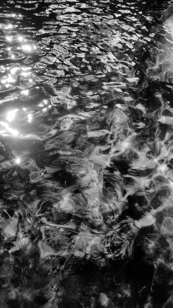 Artistic black and white ripples on water surface reflecting light, creating an abstract effect.