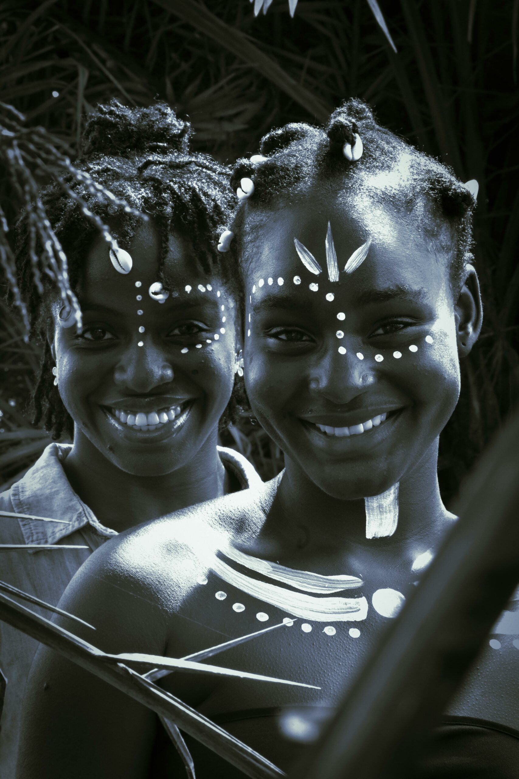 Two women with traditional face paint smiling, representing cultural beauty.