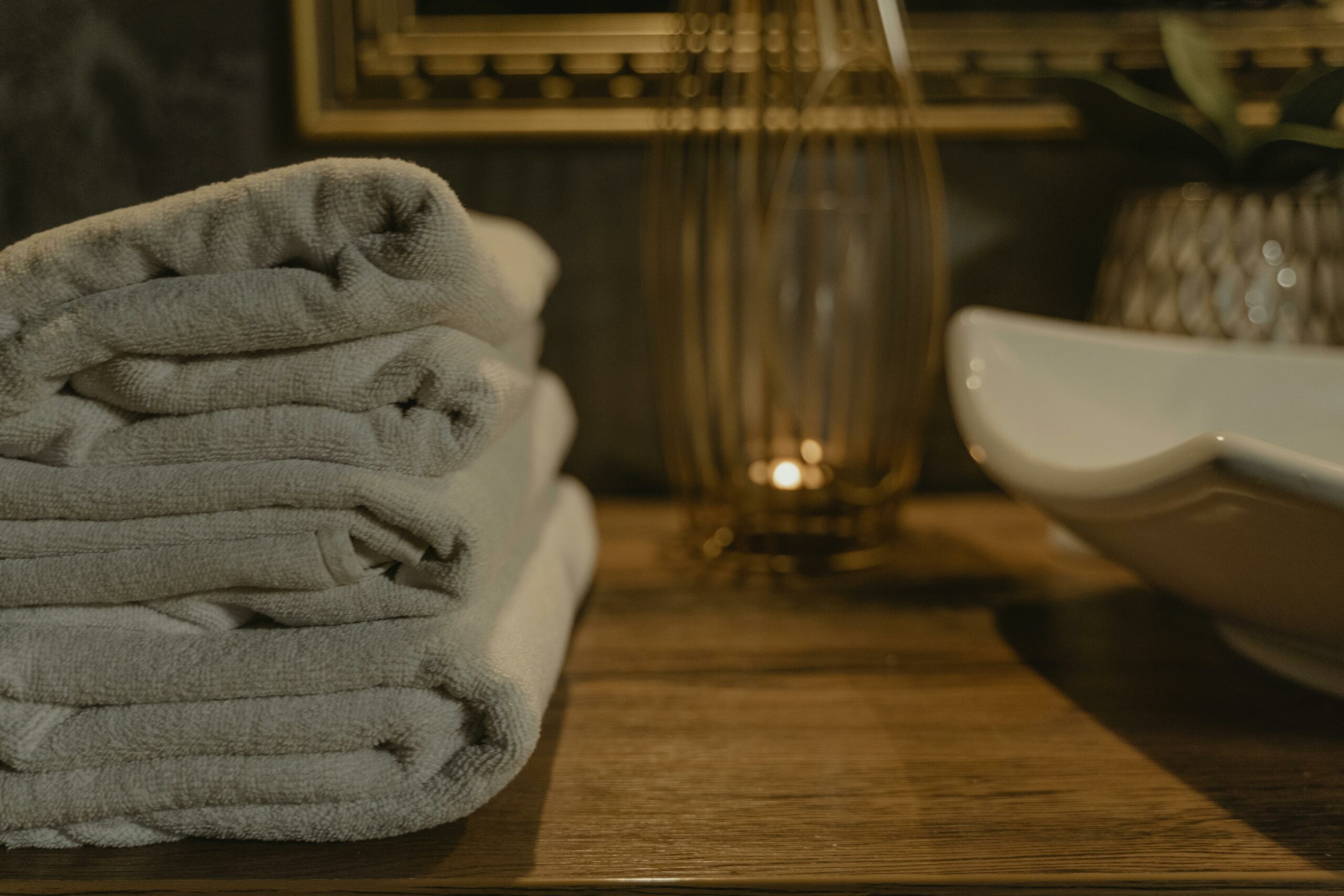 Elegant white towels neatly stacked in a cozy bathroom ambiance with soft lighting.
